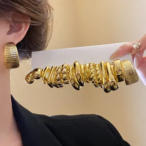 Close-up of gold irregular textured earring set on display card and worn on ear