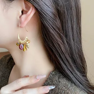 Macro view of vintage ethnic gold-plated hoop earrings with dangling stone beads