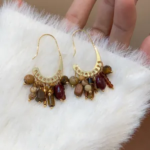 Detailed close-up of gold-plated vintage boho hook earrings with natural stone tassel accents
