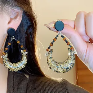 Macro view of vintage crescent moon resin earrings with gold foil accents and beaded details