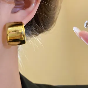 Detailed close-up showing a vintage-style chunky gold square earring with a glossy finish