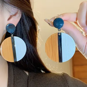 Close-up of retro geometric circular color-blocked drop earrings shown on ear and hand