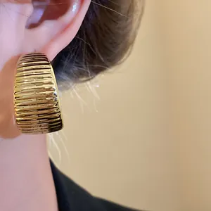 Close-up detail showing a gold ribbed hoop earring with a vintage pleated texture