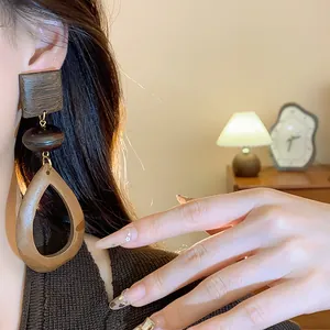 Close-up of vintage geometric wooden drop earrings on model with warm lighting