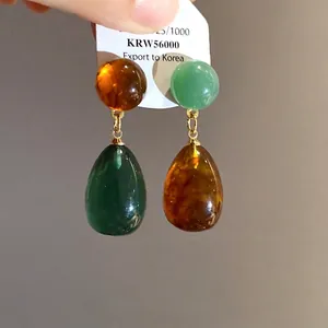 Vintage style asymmetric resin teardrop earrings in emerald green and amber hues