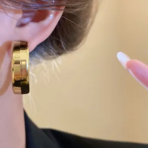Detailed close-up of a minimalist gold-colored thick hoop earring with polished finish