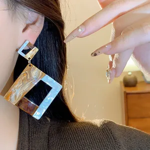 Close-up of vintage geometric acrylic square earrings with marble texture on model