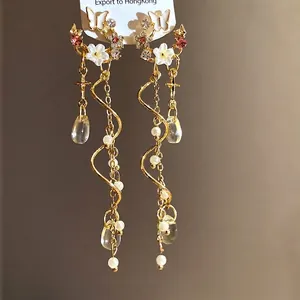 Elegant gold butterfly and flower tassel earrings with rhinestones and pearl drops decor.