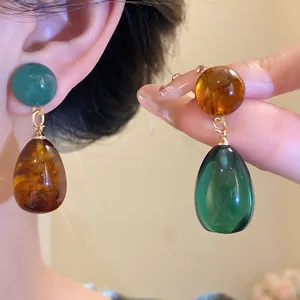 Detailed view of vintage asymmetrical resin teardrop earrings in amber and green