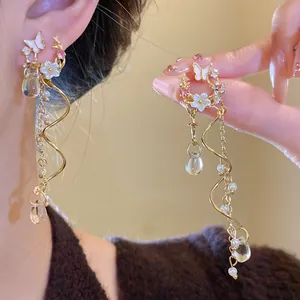 Detail of ornate gold butterfly flower tassel earrings with pearls and sparkling crystals