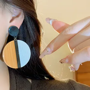 Close-up of vintage geometric round earrings with wood texture and three-color design.