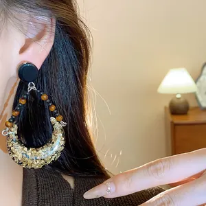 Close-up of vintage crescent drop earrings with gold foil detail worn by an Asian model