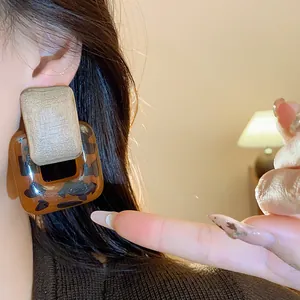 Detailed macro view of vintage geometric leopard print resin earrings worn on ear.