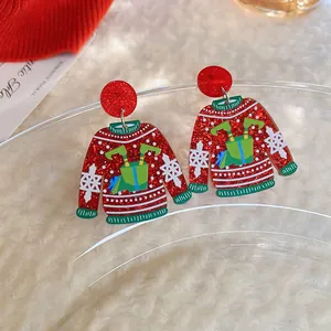 Close-up of red glittery Christmas sweater earrings with green and white snowflake details