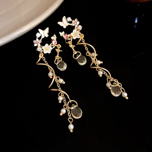 Detailed view of gold butterfly flower earrings with long pearl tassels and drop charms