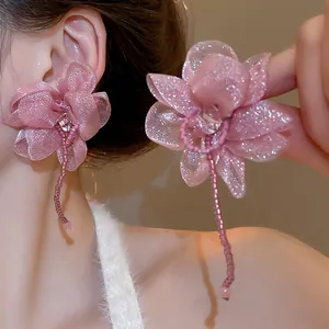 Detail of pink chiffon flower earrings with shimmering petals and delicate bead tassels.