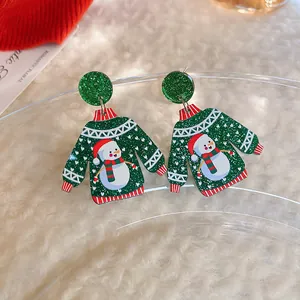 Detail of Christmas sweater-shaped earrings with cute snowman pattern and glitter finish