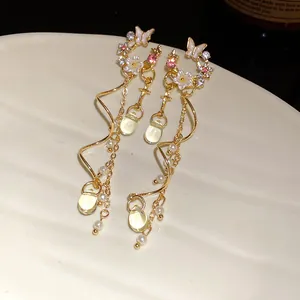 Detailed macro view of elegant gold butterfly flower tassel earrings on ceramic