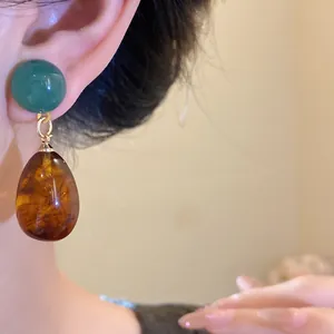 Elegant vintage resin asymmetrical water drop earrings with amber texture shown on model ear