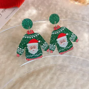 Close-up of green Christmas sweater earrings with Santa Claus pattern and glitter accents.