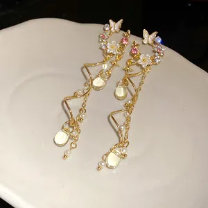 Detailed view of elegant gold-toned butterfly and flower tassel earrings with rhinestones