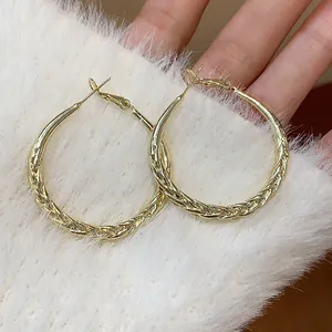Close-up of elegant gold twisted hoop earrings with silver needles for women's fashion