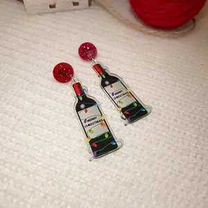 Detail view of festive acrylic wine bottle drop earrings with Merry Christmas text