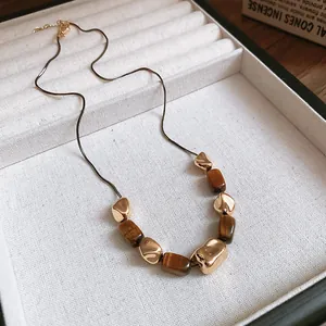 Close-up of vintage tiger eye stone necklace with gold irregular metal beads on a jewelry tray