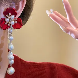 Close-up of red flower earrings with rhinestone and pearl drop tassels in vintage style