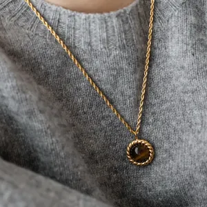Detailed macro shot of a vintage tiger eye stone pendant on a twisted gold rope chain