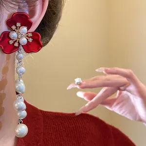 Close-up of vintage red flower earrings with long pearl tassel on a model