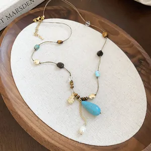 Detailed view of a vintage court style necklace with tiger eye and turquoise stones.