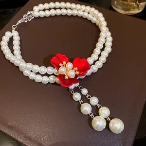Macro view of vintage double-strand pearl necklace with an elegant red flower pendant.