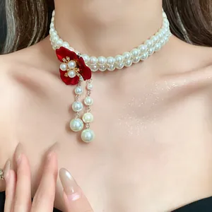 Close-up of retro double-strand pearl choker with red flower and dangling drops.