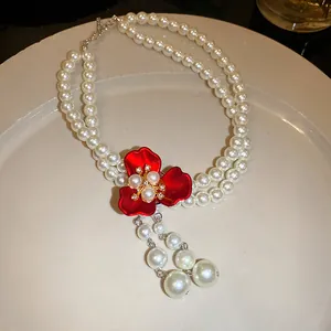 Detailed shot of double strand pearl necklace with a vibrant red flower tassel pendant
