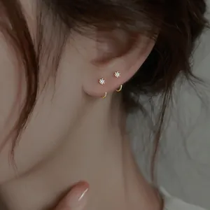 Close-up of minimalist gold zircon ear hooks worn on a female ear for a delicate daily look.