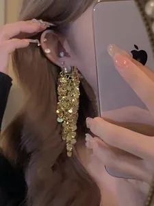 Detailweergave van lange gouden lovertjes kwastjes oorbellen met fonkelende diamanten