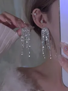 Detailopname van zilverkleurige lange kwastjes oorbellen met fonkelende strass