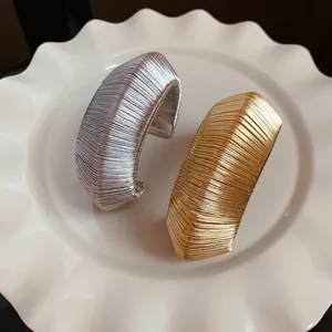 Elegant gold and silver metal wire woven open cuff bracelets on a white plate decor