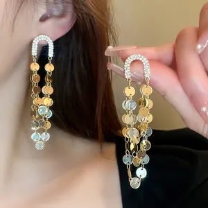 Detailopname van elegante gouden kwastjes oorbellen met strass en metalen schijfjes