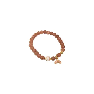 Elegant beaded elastic bracelet with peach quartz, pearl, and gold fishtail charm.