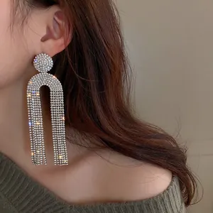 Detailoverzicht van lange zilverkleurige kwastjesoorbellen met fonkelende strass