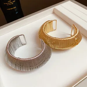 Detailed view of two metallic wire wrapped open cuff bracelets in gold and silver finish
