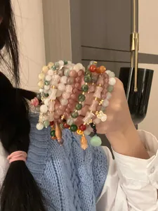 Close-up hand-held view of assorted colorful jade beaded bracelets featuring gourd charms