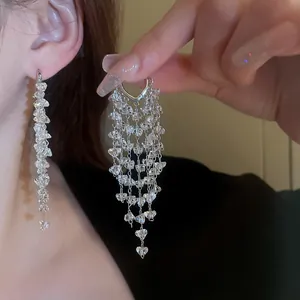 Detailweergave van elegante lange zilveren kwastoorbellen met fonkelende kristallen