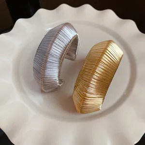 Close-up of elegant gold and silver wire-wrapped metal open cuff bracelets for women