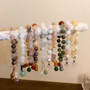 Macro shot of elegant Chinese style jade beaded bracelets hanging on a white branch