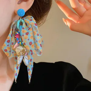 Detailed view of colorful ribbon bow earring featuring beads and natural sea shells