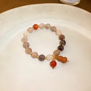 Detailed view of a Chinese style elastic jade beaded bracelet with a gourd charm.