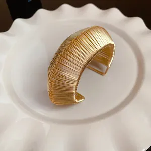 Detailed view of a minimalist wide gold woven wire open cuff bracelet for women.